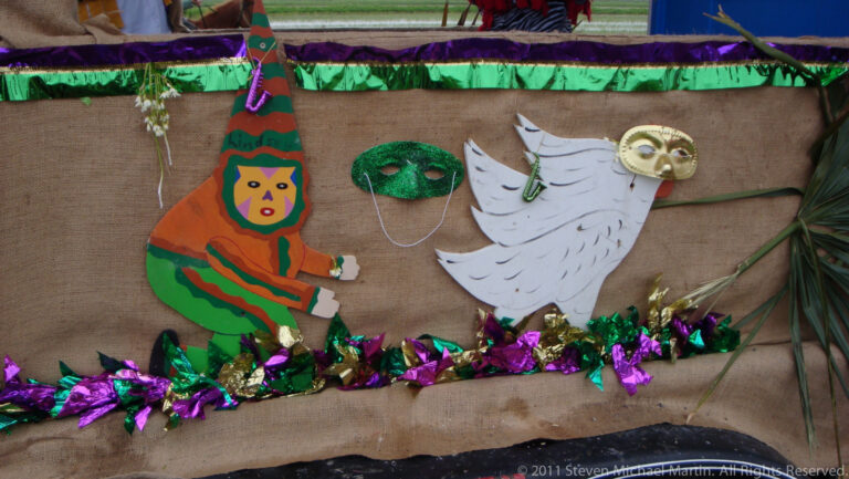 Painted figures and three colorful masks decorate a burlap panel above metallic garland.