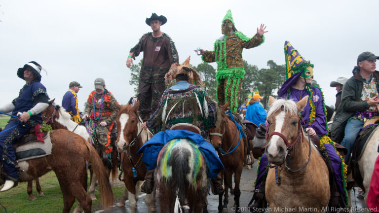 Costumed horseback riders cluster together as a participant in green raises a hand.