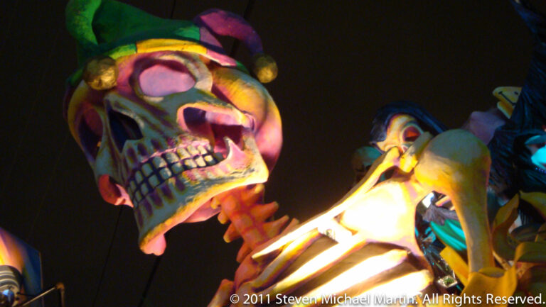 A brightly colored skull with a patterned jester-like cap fills the nighttime frame.
