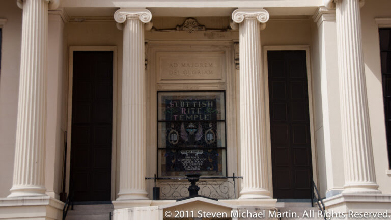 Fluted columns frame the Scottish Rite Temple entrance, with a Latin inscription and a window sign naming the building.