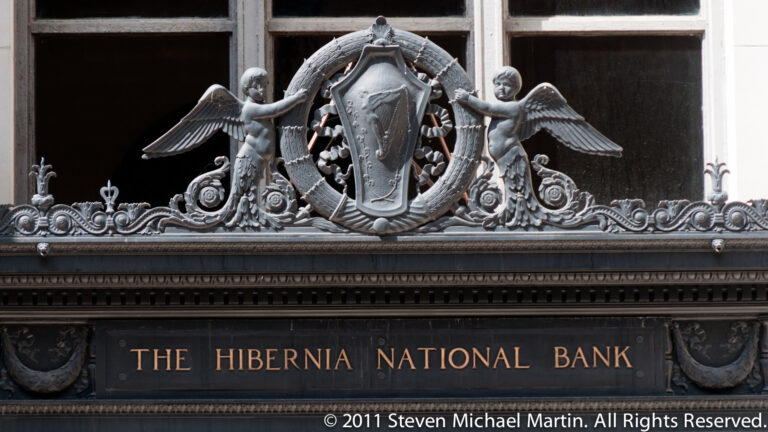 Two winged stone figures flank a shield above the engraved name The Hibernia National Bank.