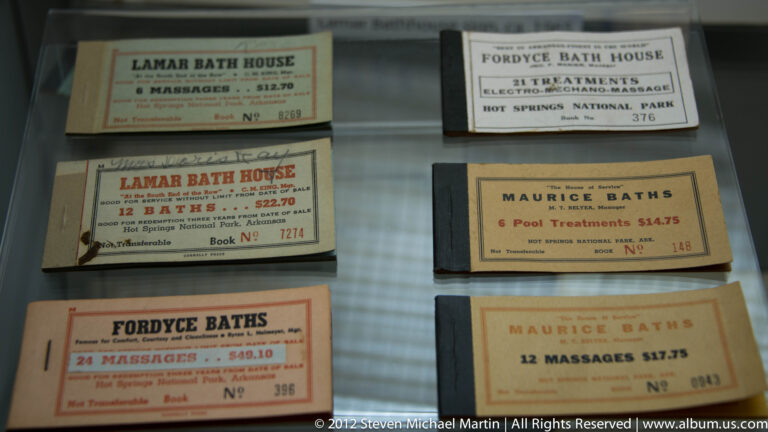 Printed bathhouse tickets under glass name Fordyce, Lamar, and Maurice Baths and list treatments and prices.