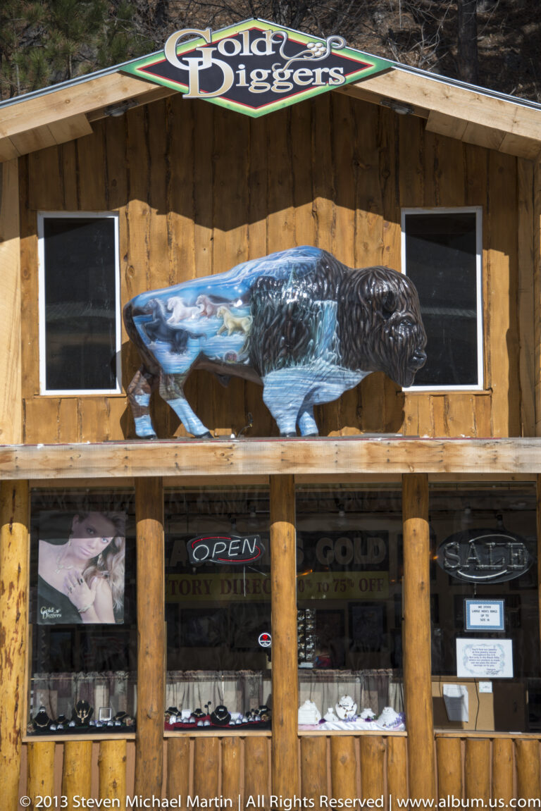 A blue bear sculpture stands above the Gold Diggers storefront and its display windows.