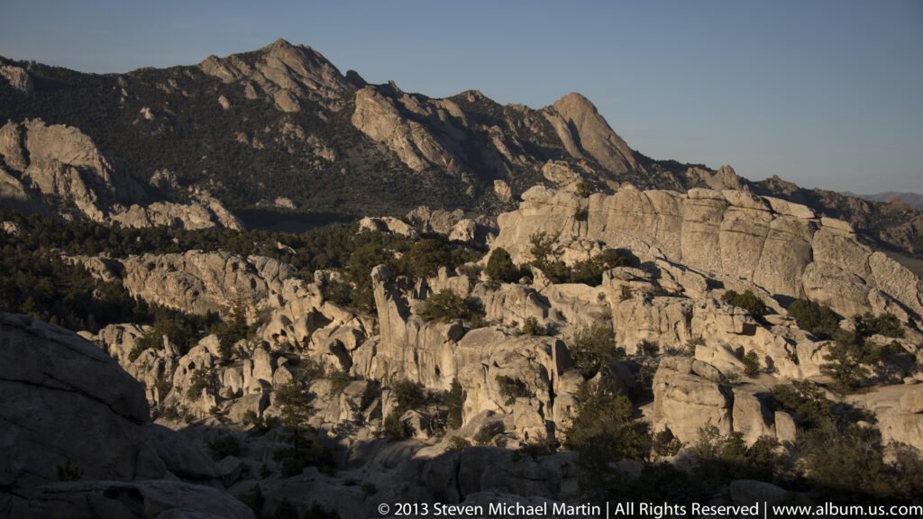 Numerous granite spires spread across a valley beneath a dark mountain ridge.
