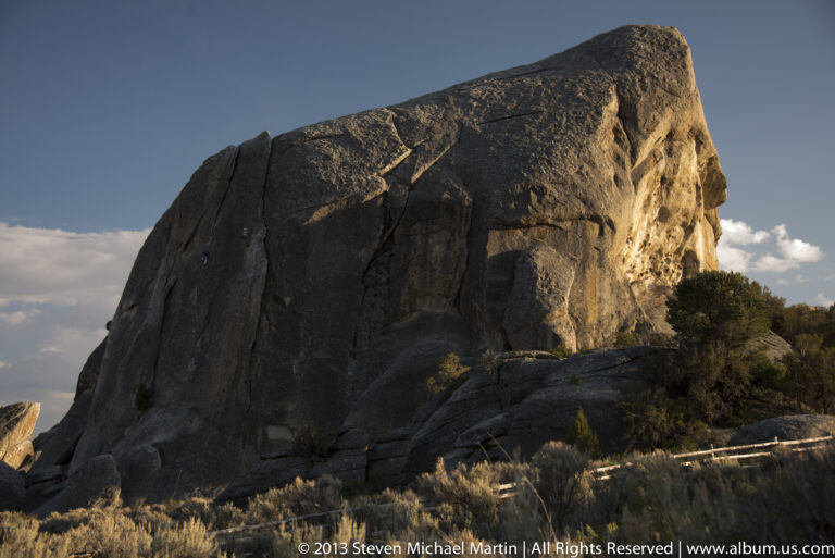 A broad granite wall catches golden light above a shadowed rocky slope.