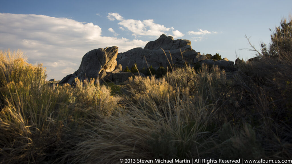 Golden grasses glow in front of a dark granite ridge at sunset.