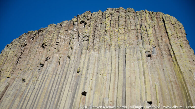 Parallel rock columns and dark fissures fill the steep face of Devils Tower.