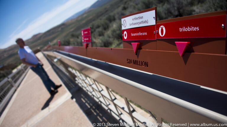 A visitor leans beside a timeline railing labeled “trilobites,” “extinction,” and “520 million.”