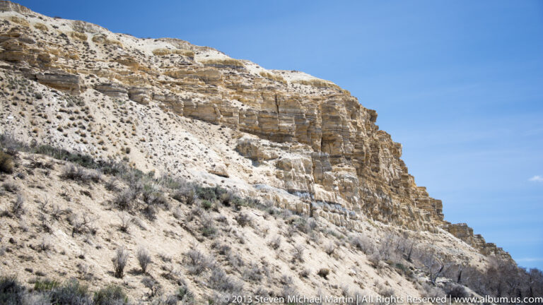 A pale cliff with visible horizontal strata rises above a brush-covered slope.