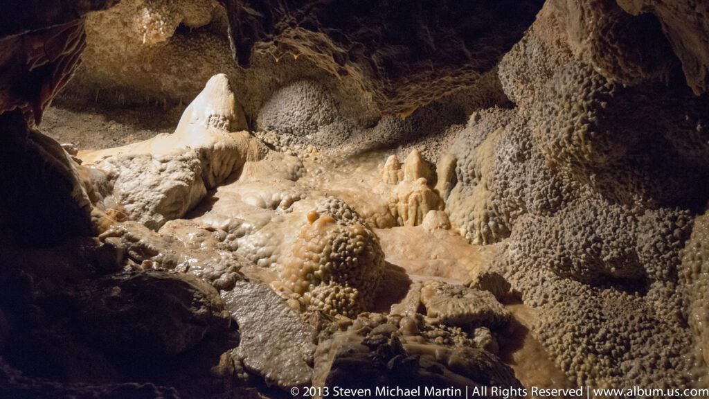 Pale flowstone and rounded deposits fill a cave passage framed by dark rock.
