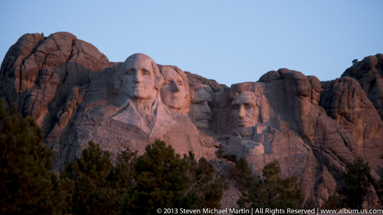 Warm evening light illuminates the carved presidential faces while the surrounding granite falls into shadow.