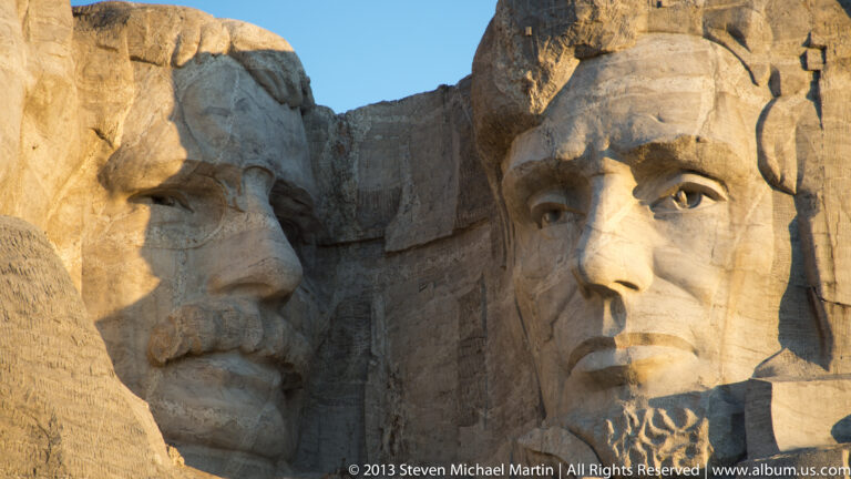 Thomas Jefferson’s profile and Theodore Roosevelt’s carved face appear close together in warm sunlight.