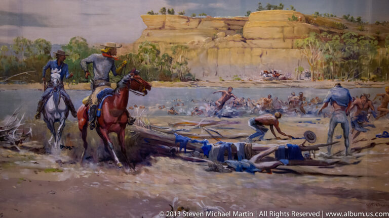 A historical painting shows mounted figures and a group gathered beside a river below sandstone cliffs.