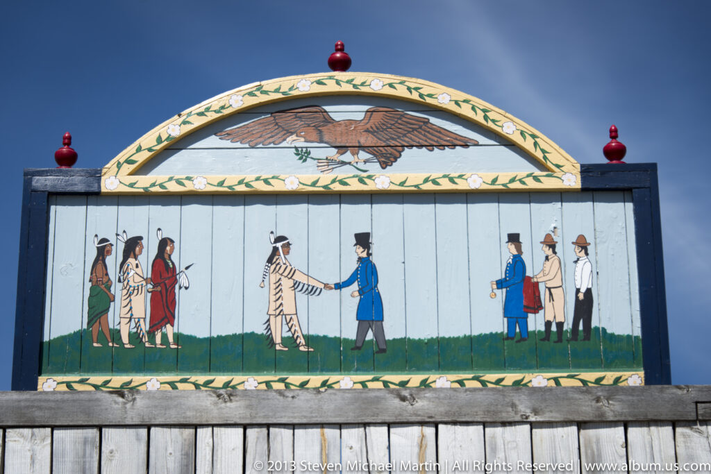A painted mural shows Indigenous visitors and traders facing one another beneath an eagle motif.