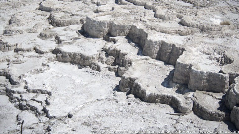 Shallow water channels divide irregular pale travertine ledges into several stepped basins and pools.