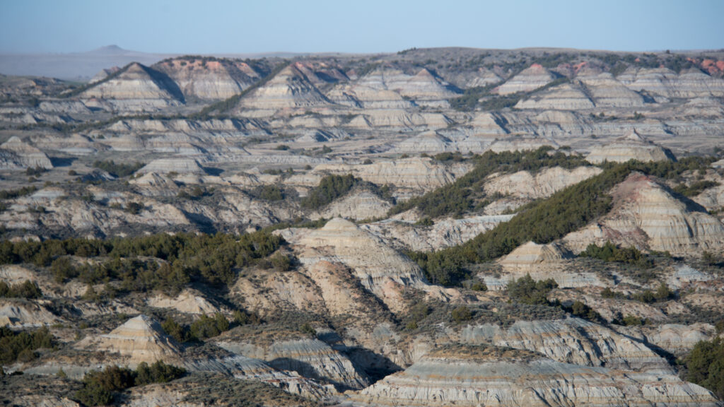 Layered badlands ridges and ravines extend across a broad, sparsely vegetated landscape.