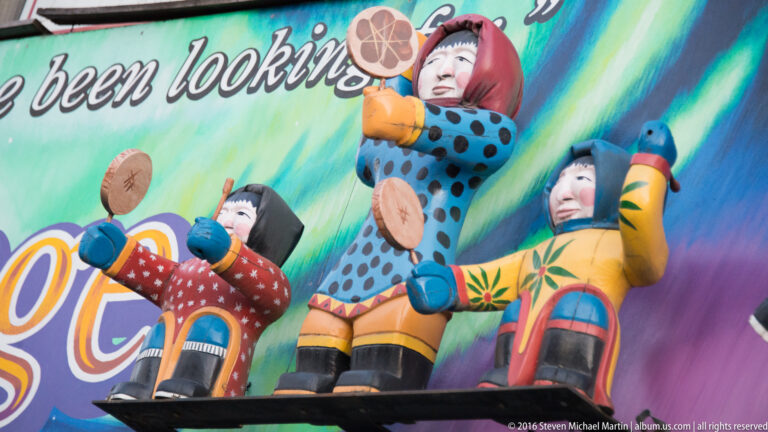 A colorful mural shows stylized figures in bright clothing against a turquoise background, with a blue animal at right.