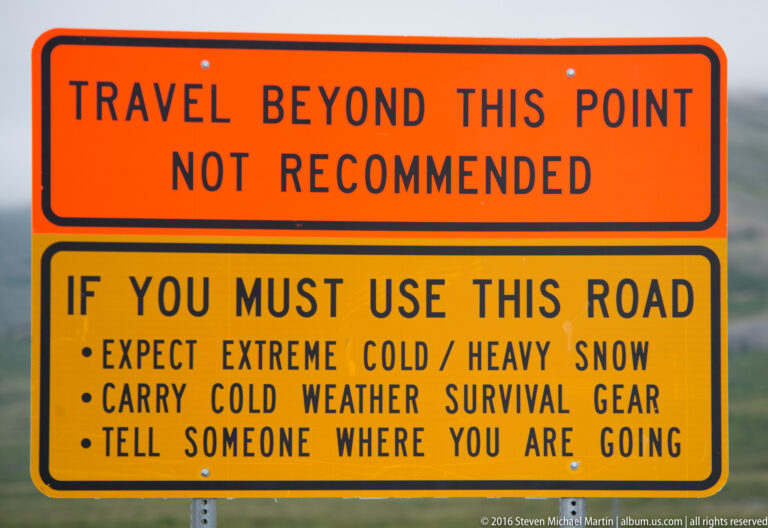 An orange warning sign advises against travel and lists cold-weather road precautions.