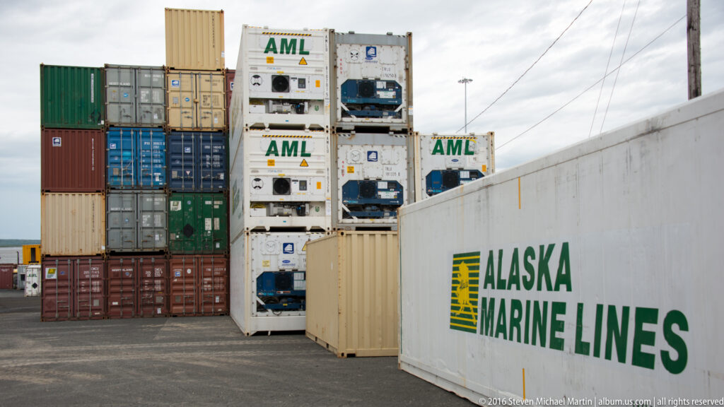 Alaska Marine Lines container in the foreground with stacked freight and refrigerated containers behind it.