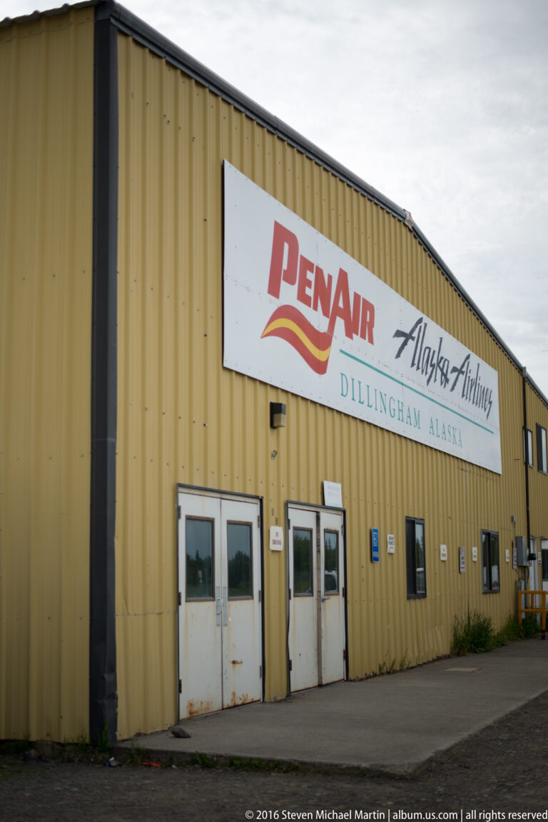 Long yellow airport building with a prominent PenAir and Alaska Airlines sign for Dillingham.