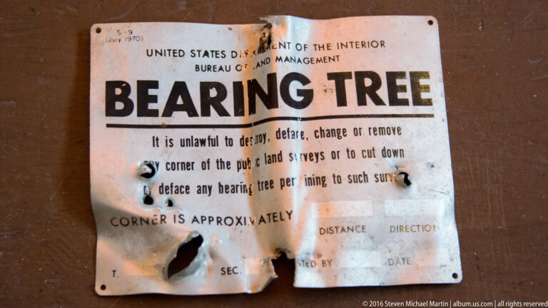 Weathered Bureau of Land Management sign headed BEARING TREE, with a notice about public-land survey markers.