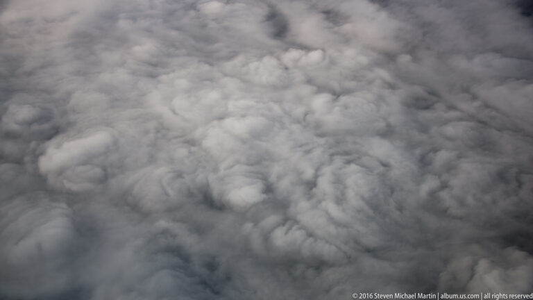 White and gray cloud tops fill the frame in an aerial view with no visible horizon or ground.