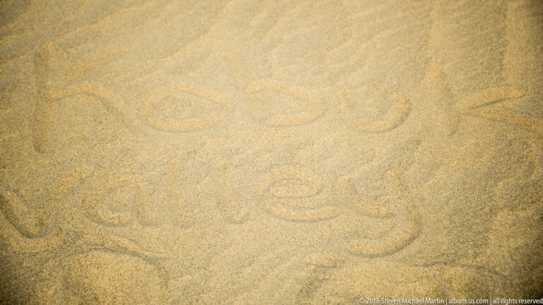 Shallow serpentine grooves loop across a fine sandy surface, forming broad repeated curves with no person visible.