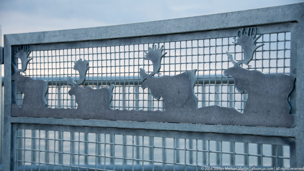 Cutout caribou silhouettes decorate a gray metal gate above a square wire grid.