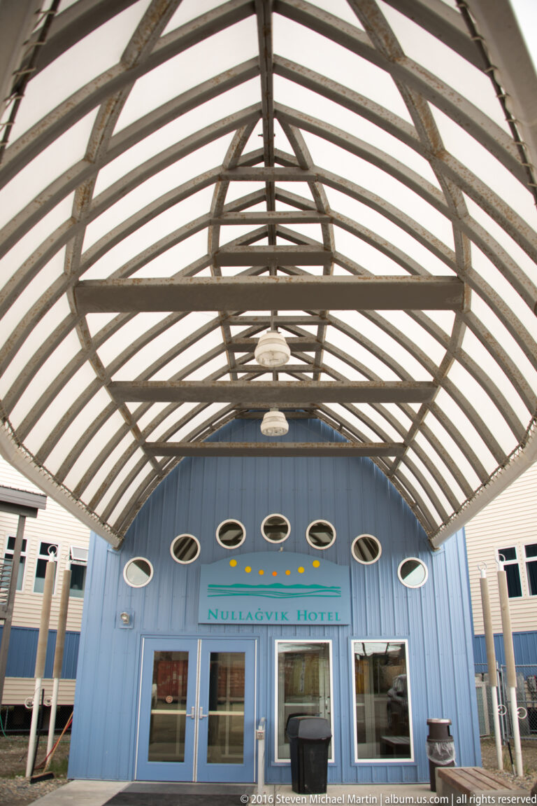 Ribbed canopy beams lead toward the Nullagvik Hotel entrance and a row of oval windows.