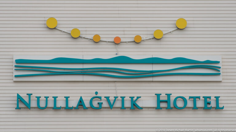 Turquoise Nullagvik Hotel lettering sits beneath colored circles and above a stylized wave motif.