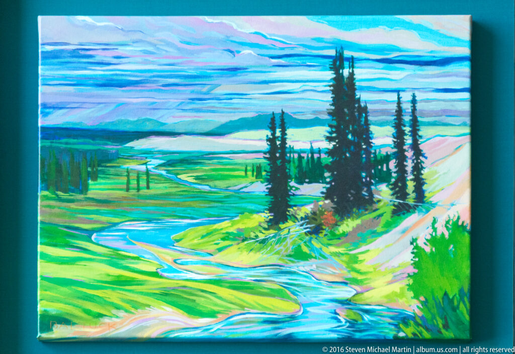 A landscape artwork shows a winding river crossing a green valley with conifers and distant hills.