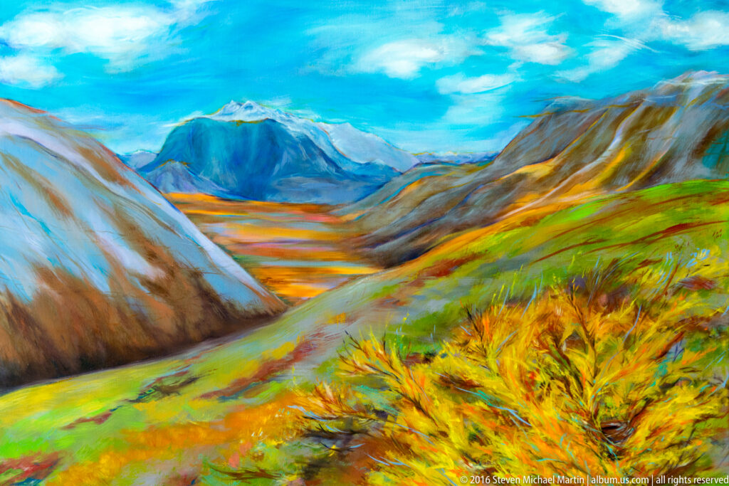 A colorful painting shows an autumn-toned valley between steep mountains beneath blue sky.