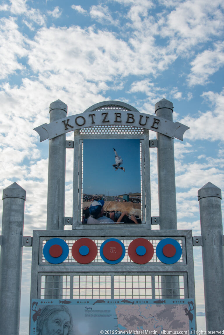 A metal gateway labeled Kotzebue displays a central photograph and decorative circular motifs above information panels.