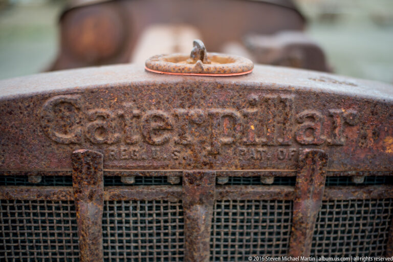 Raised lettering and a small circular cap appear on a rusted machine housing above a grille.
