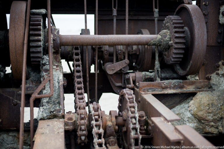 Rusted gears, a horizontal shaft, and heavy chain are packed inside an old machine.