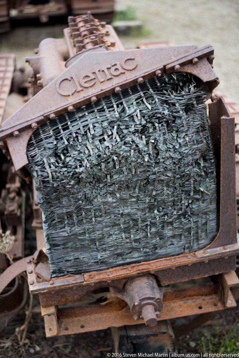 A curved wire-mesh screen marked “Cleveland” sits in a rusted frame with fragments caught in the mesh.