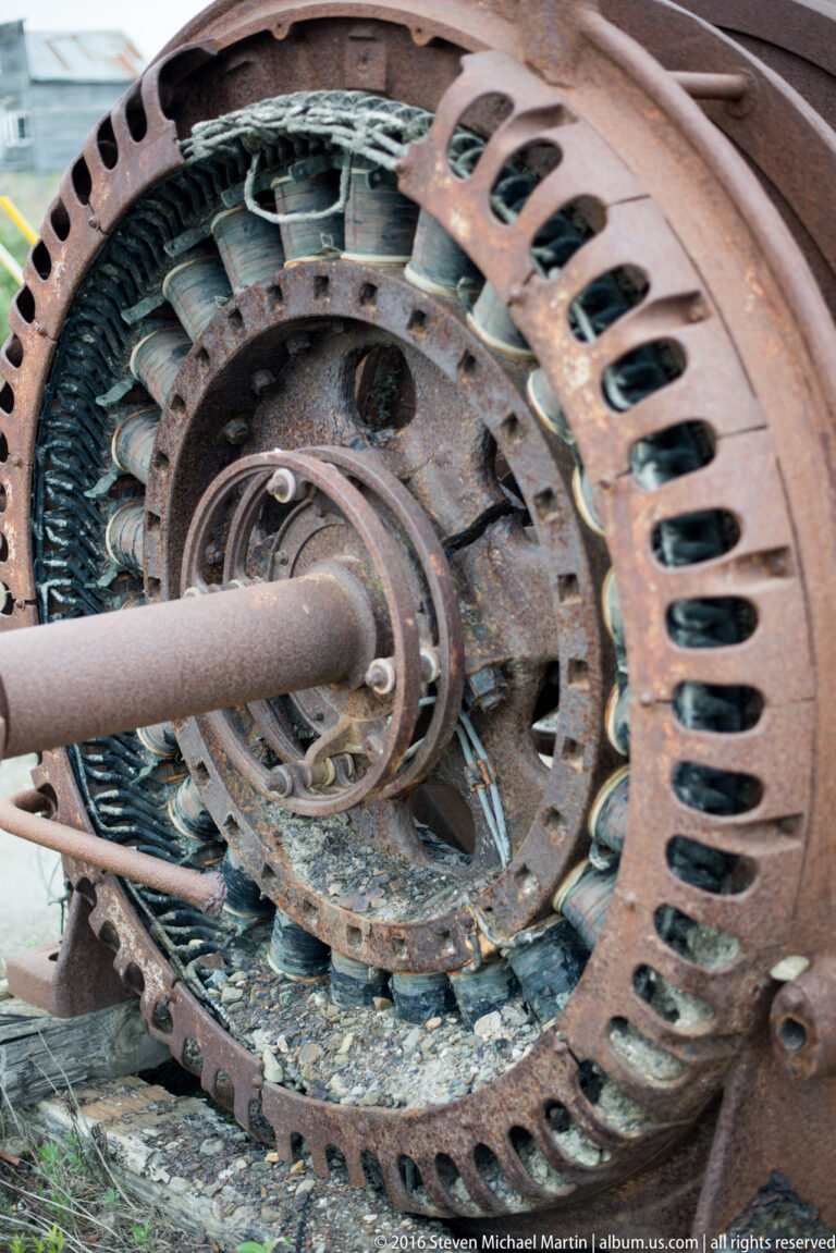 A large rusted circular machine housing reveals inner rings, coils, and a perforated outer rim.