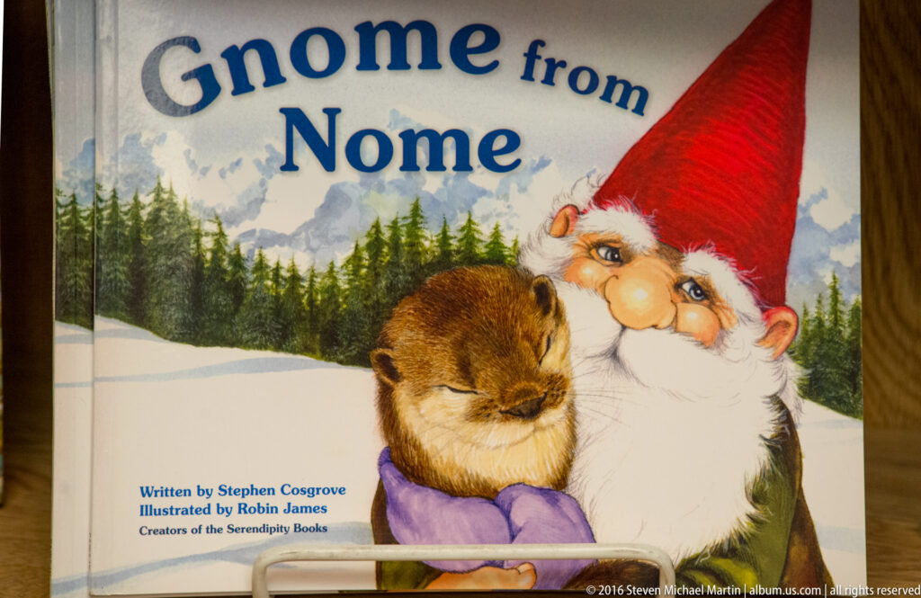 A colorful book cover reads “Home from Nome” above a gnome holding a small brown animal in snow.