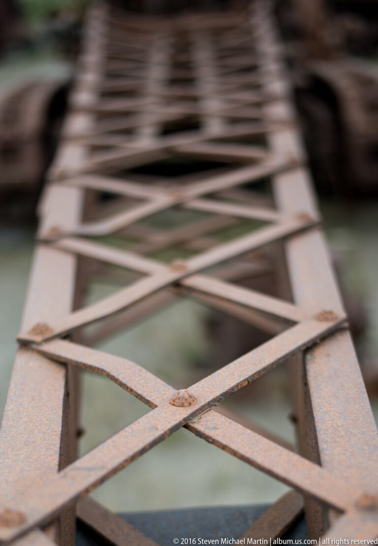Diagonal steel braces form a repeating lattice that fades into shallow focus.