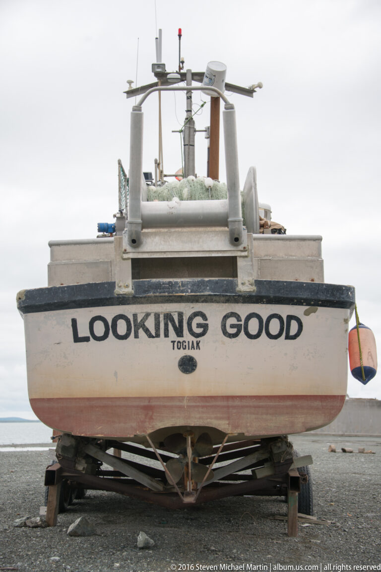 A white cabin boat named “Looking Good” rests on a cradle with antennas above its roof.