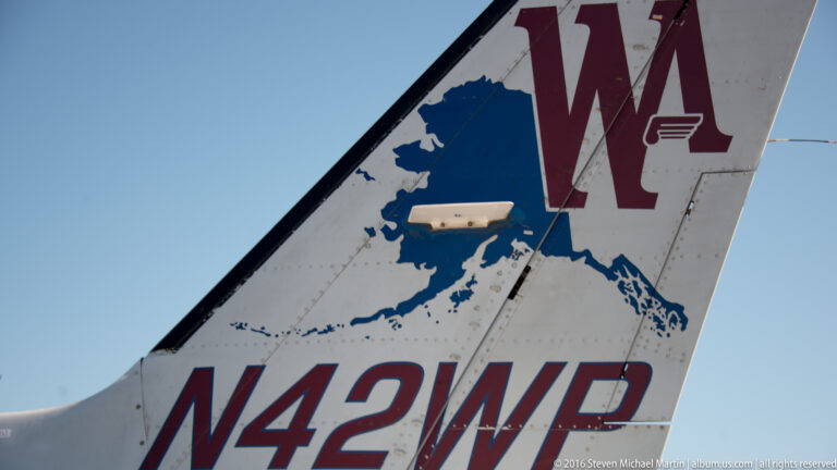 Close-up of an airplane tail with an Alaska map, burgundy initials, mountain graphic, and registration N42WP.