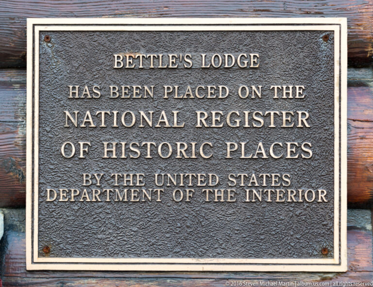 A metal plaque on log siding states that Bettles Lodge is on the National Register of Historic Places.