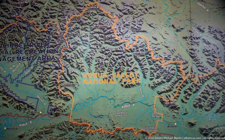 A shaded relief map outlines Kobuk Valley National Park in orange among neighboring Alaska public lands.