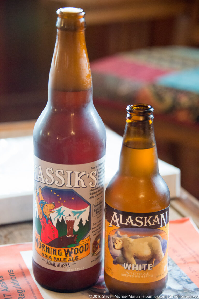 Two amber bottles with colorful illustrated labels stand on papers on a wooden table.