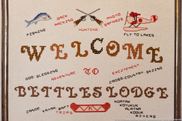 Embroidered welcome sign for Bettles Lodge with stitched labels and outdoor activity motifs.
