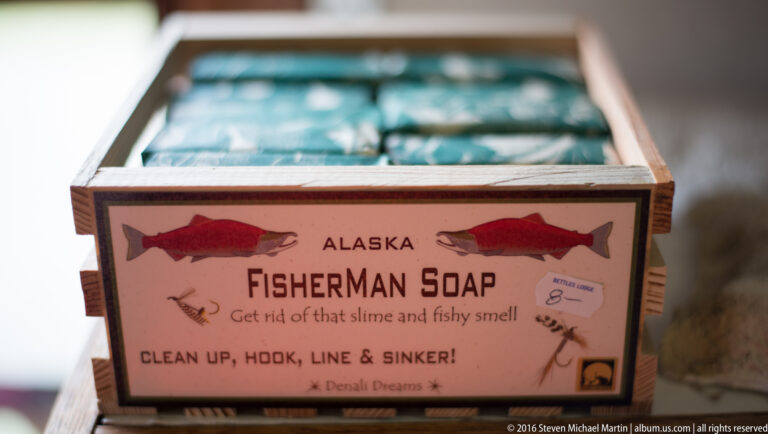 Wrapped soap bars sit in a display box beneath an “Alaska Fisherman Soap” sign illustrated with fish.