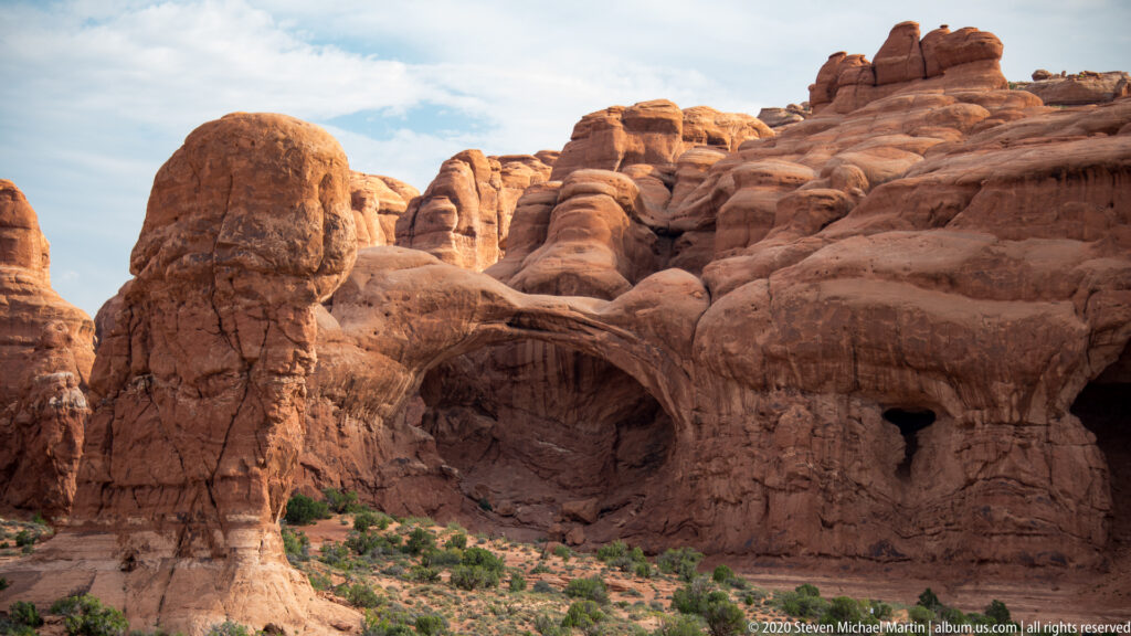 Two overlapping sandstone arches create nested openings within massive red rock walls.