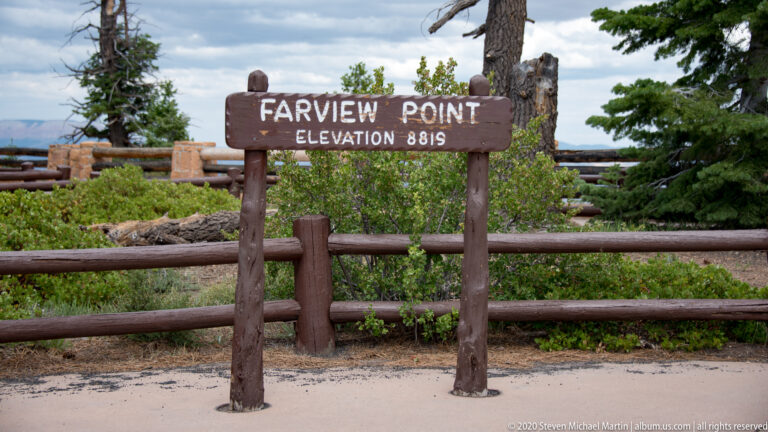 A wooden Farview Point marker lists an elevation of 8,819 feet behind a log barrier and evergreen shrubs.