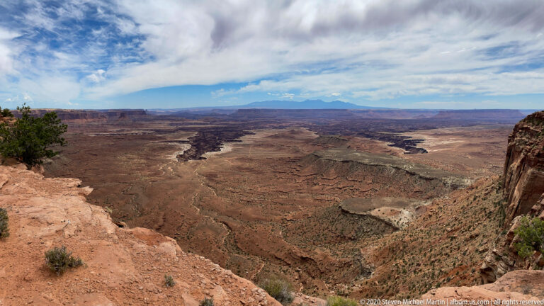 A rocky rim overlooks a deep basin of mesas and branching canyons.