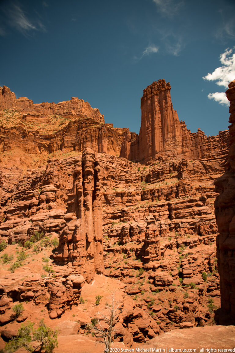 A tall sandstone pillar stands among orange ledges and deep shadowed clefts.